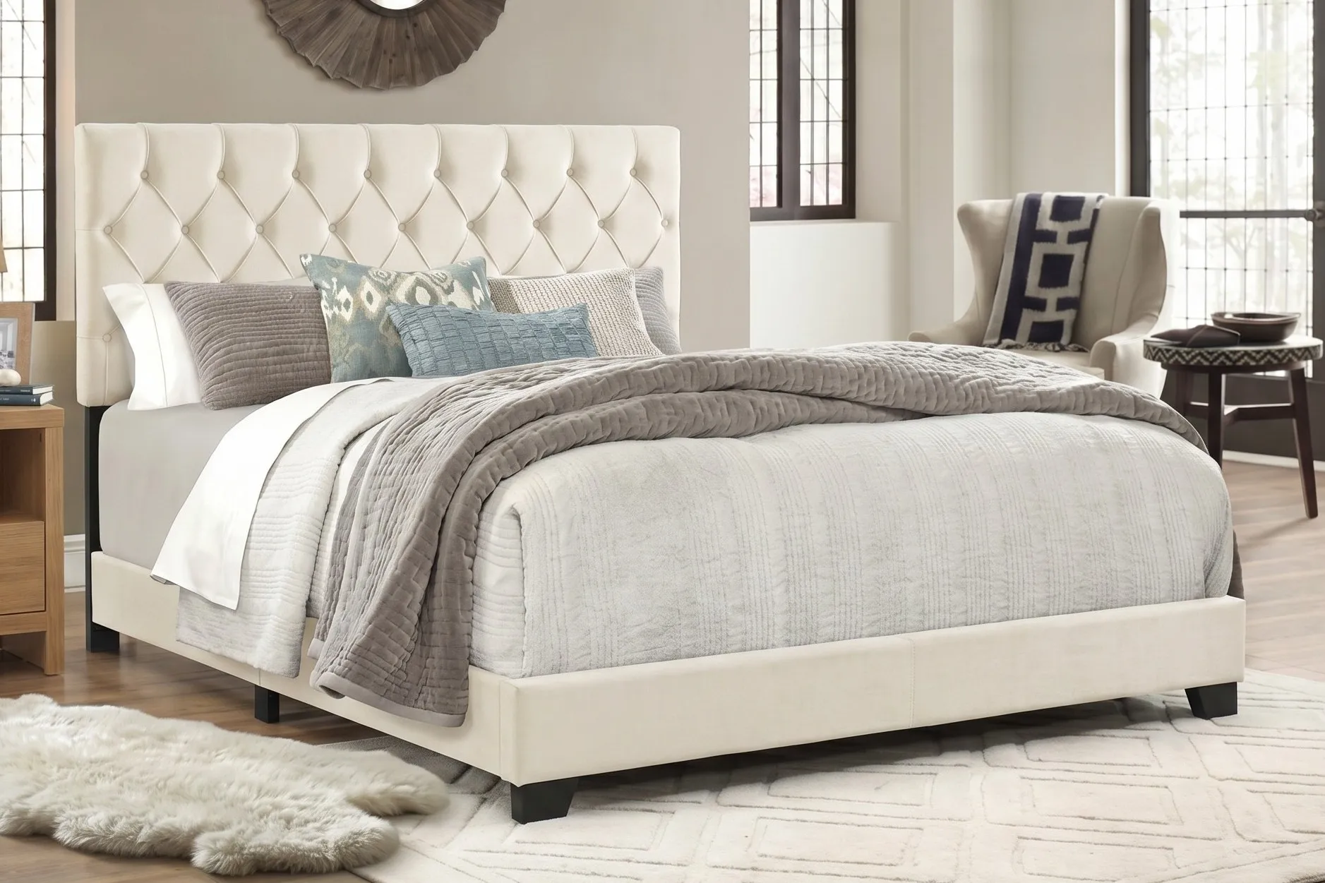 Ivory upholstered bed frame with a button-tufted headboard in a bright bedroom