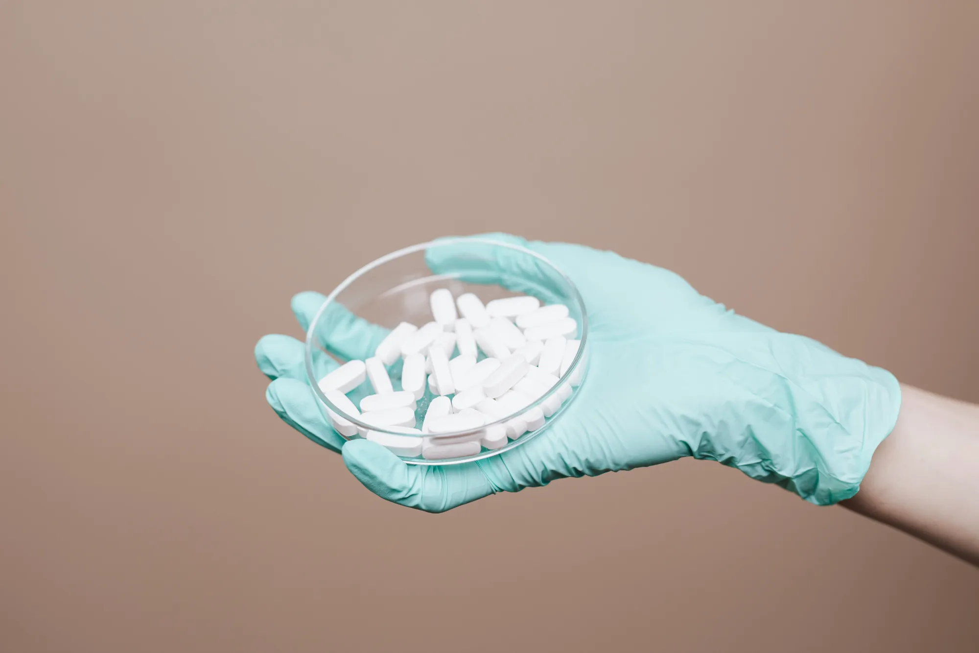 Gloved hand holding a dish of tablets