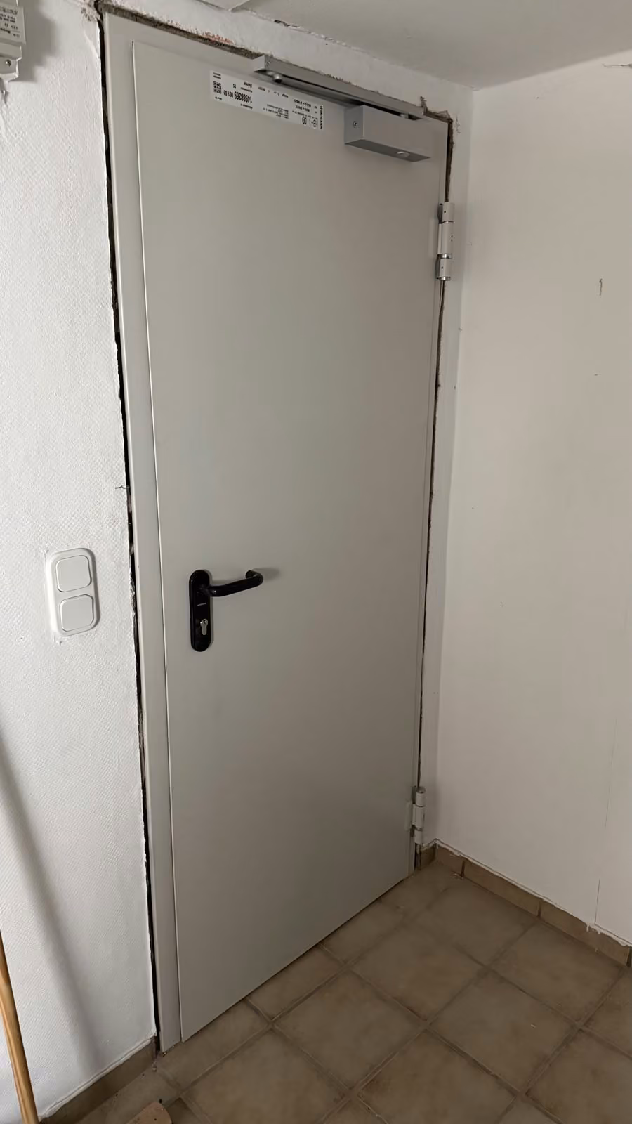 Brandschutzt&uuml;r mit Obent&uuml;rschlie&szlig;er in einem Kellerflur