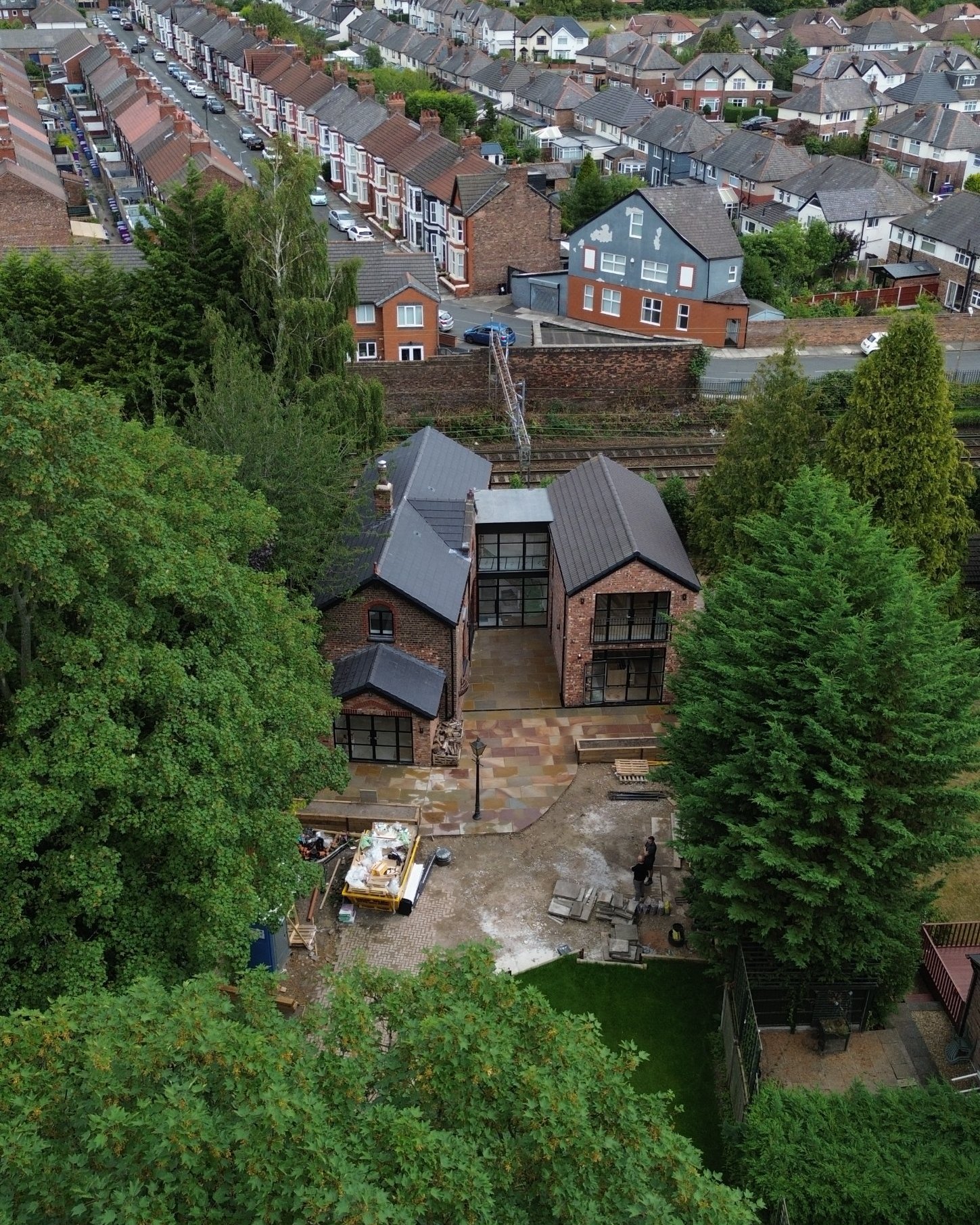 The Coach House from above, set among mature trees beside the railway