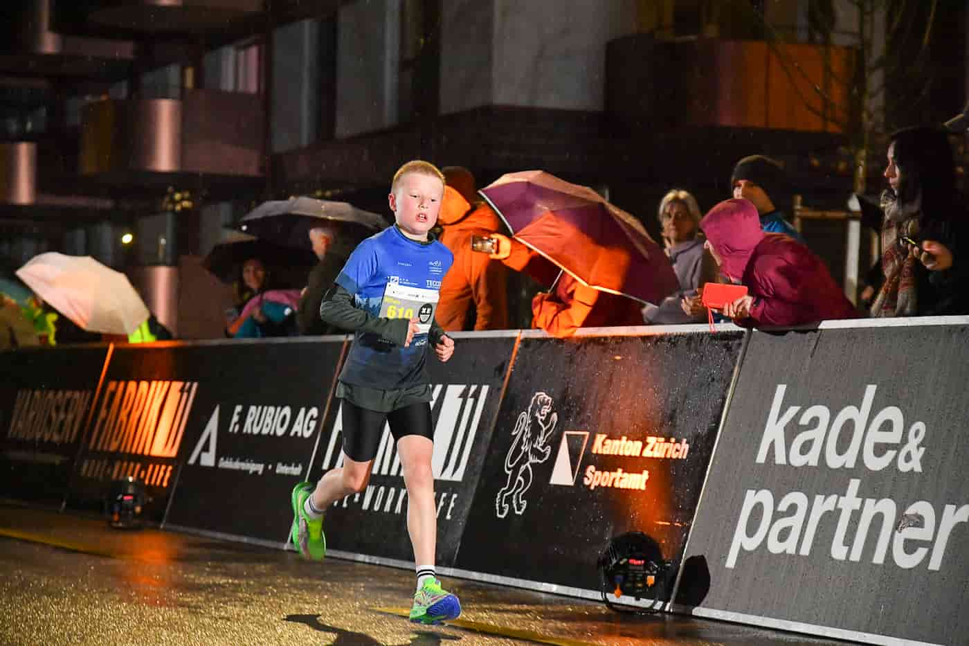 Kind läuft im Regen am Streckenrand vorbei beim NightRun in Dübendorf