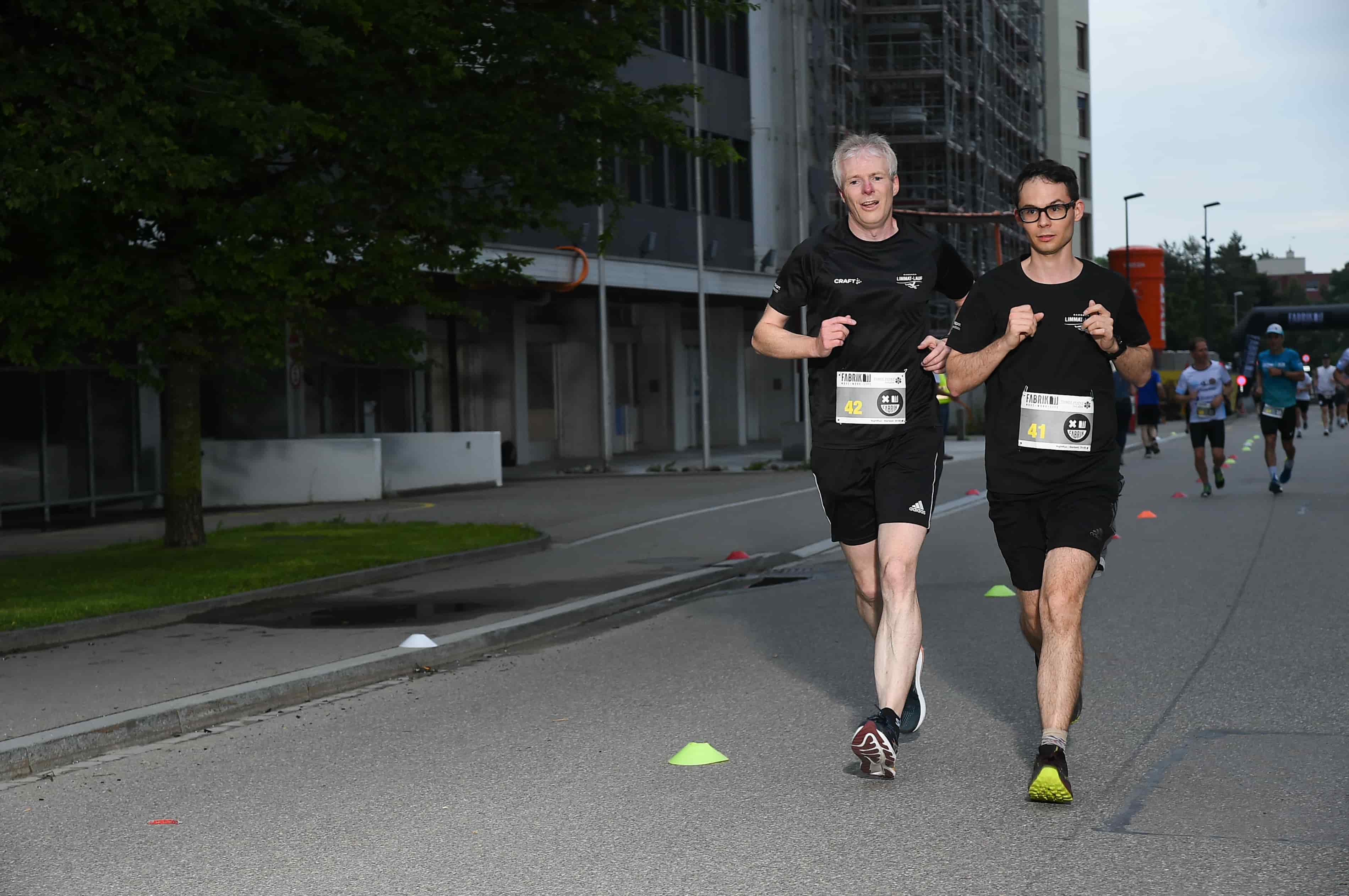 Zwei Läufer mit Startnummern in der Abenddämmerung, NightRun Zürich 2024 in Dübendorf