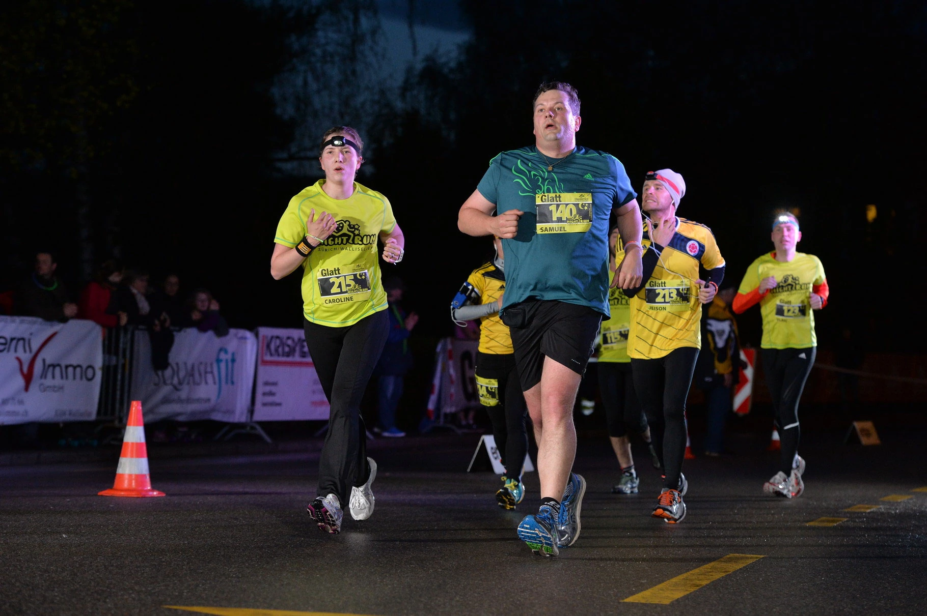 NightRun Wallisellen 2016: Vier Läufer in gelben Shirts nebeneinander in der Nacht
