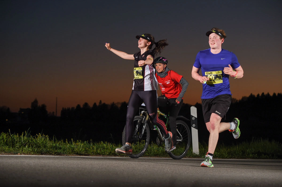 NightRun 2017 Wallisellen: Läuferinnen und Läufer mit Radfahrer in der Dämmerung