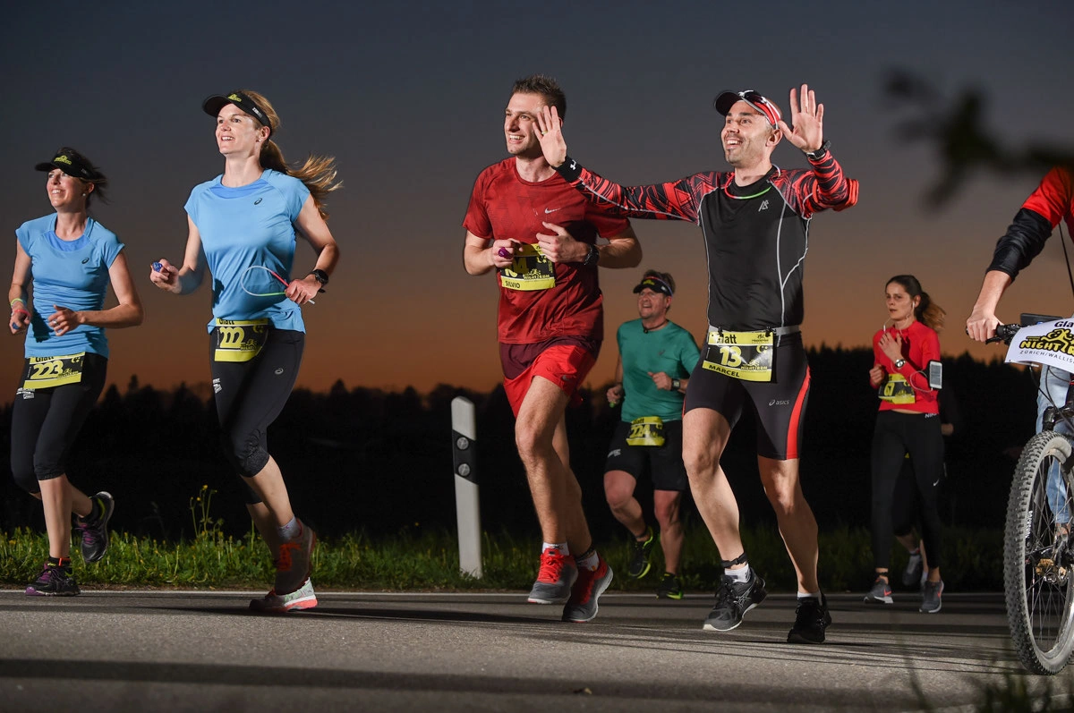 NightRun 2017 Wallisellen: Läufergruppe in bunten Shirts in der Dämmerung
