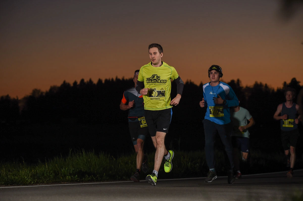 NightRun 2018 Wallisellen: Läufer im gelben Shirt mit Begleitern in der Abenddämmerung