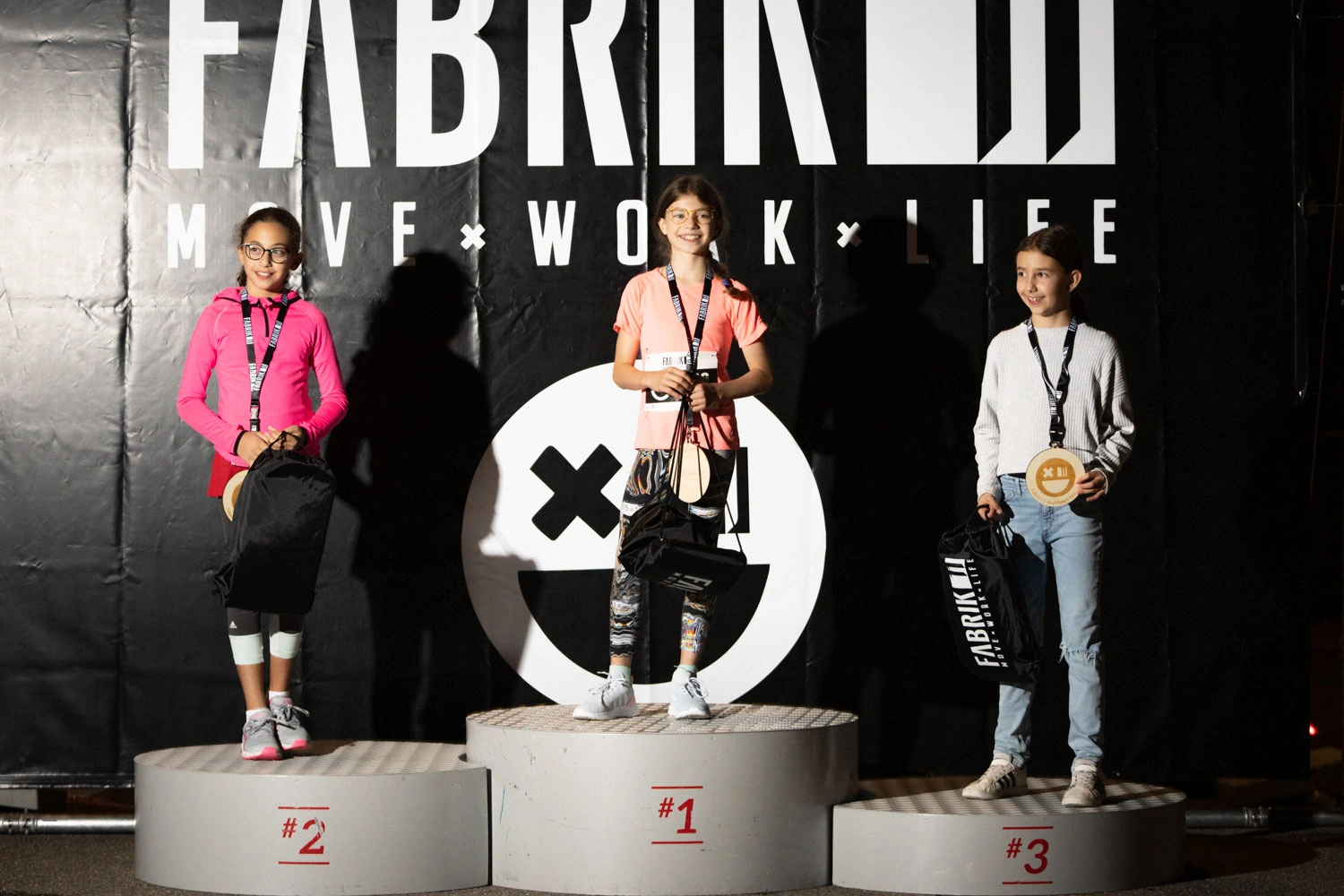 NightRun Dübendorf 2021: Siegerpodest mit drei Läuferinnen und Läufern vor der FABRIK11 Wand
