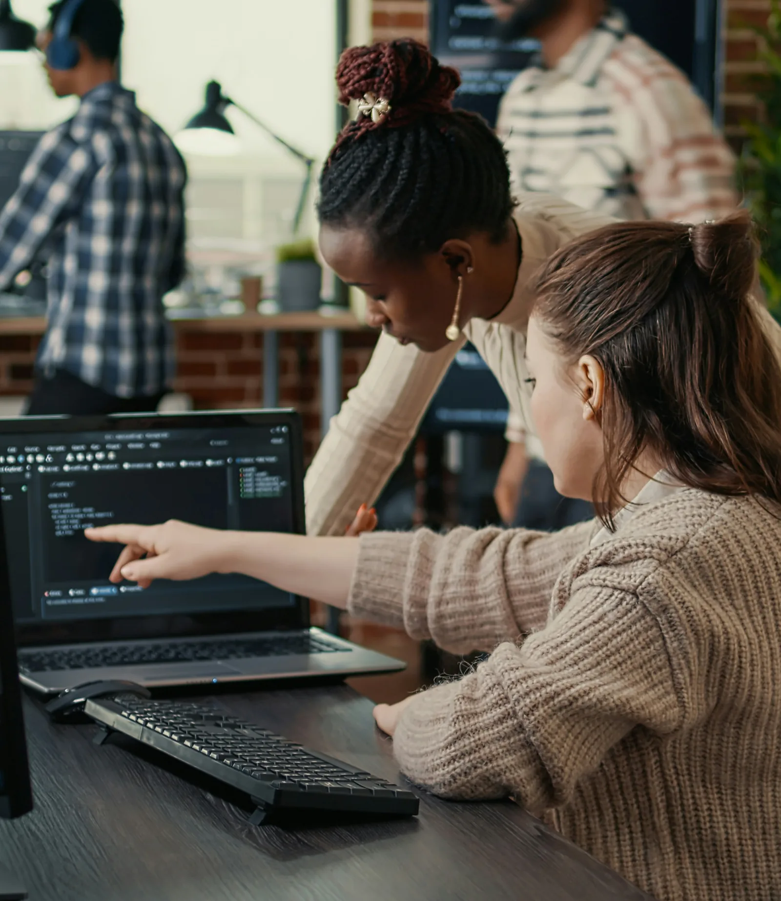 Deux développeuses travaillant ensemble sur du code devant un ordinateur portable