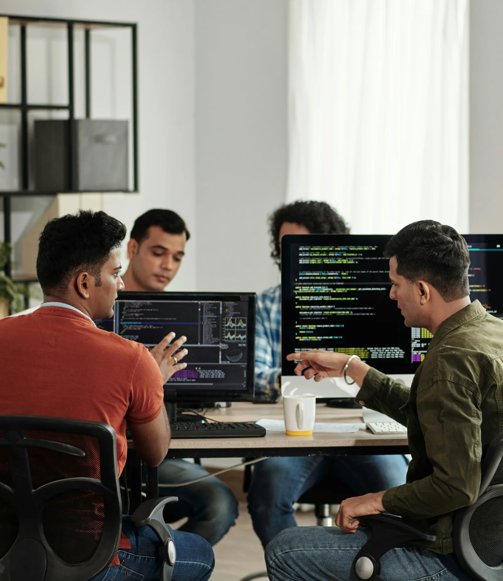 Équipe de développeurs échangeant devant des écrans affichant du code