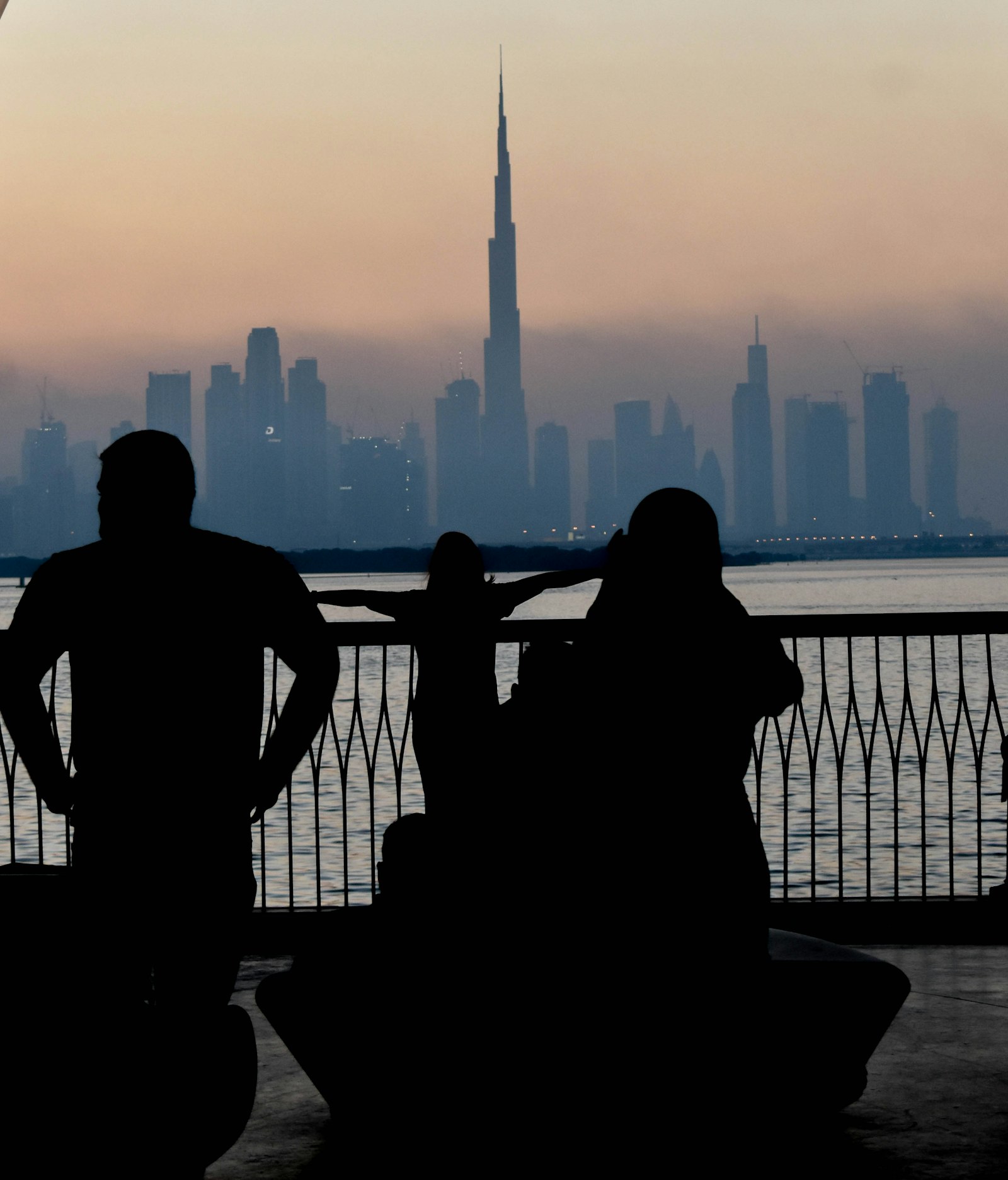 People taking in the Dubai skyline beside the water at sunset
