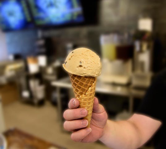 Hand holding a scoop of ice cream in a cone