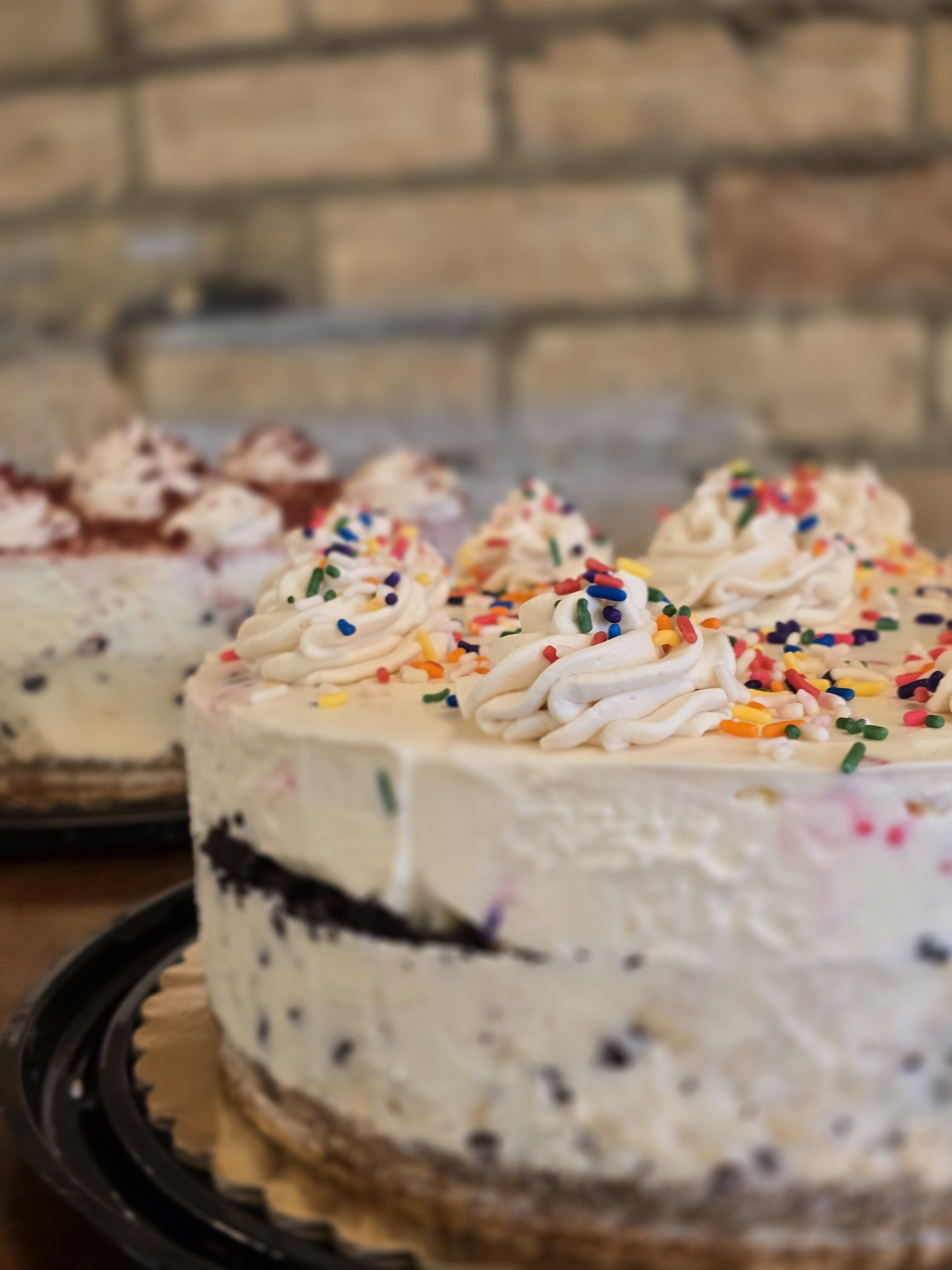 Fletcher's ice cream cake topped with whipped swirls and rainbow sprinkles, with more ice cream cakes behind it