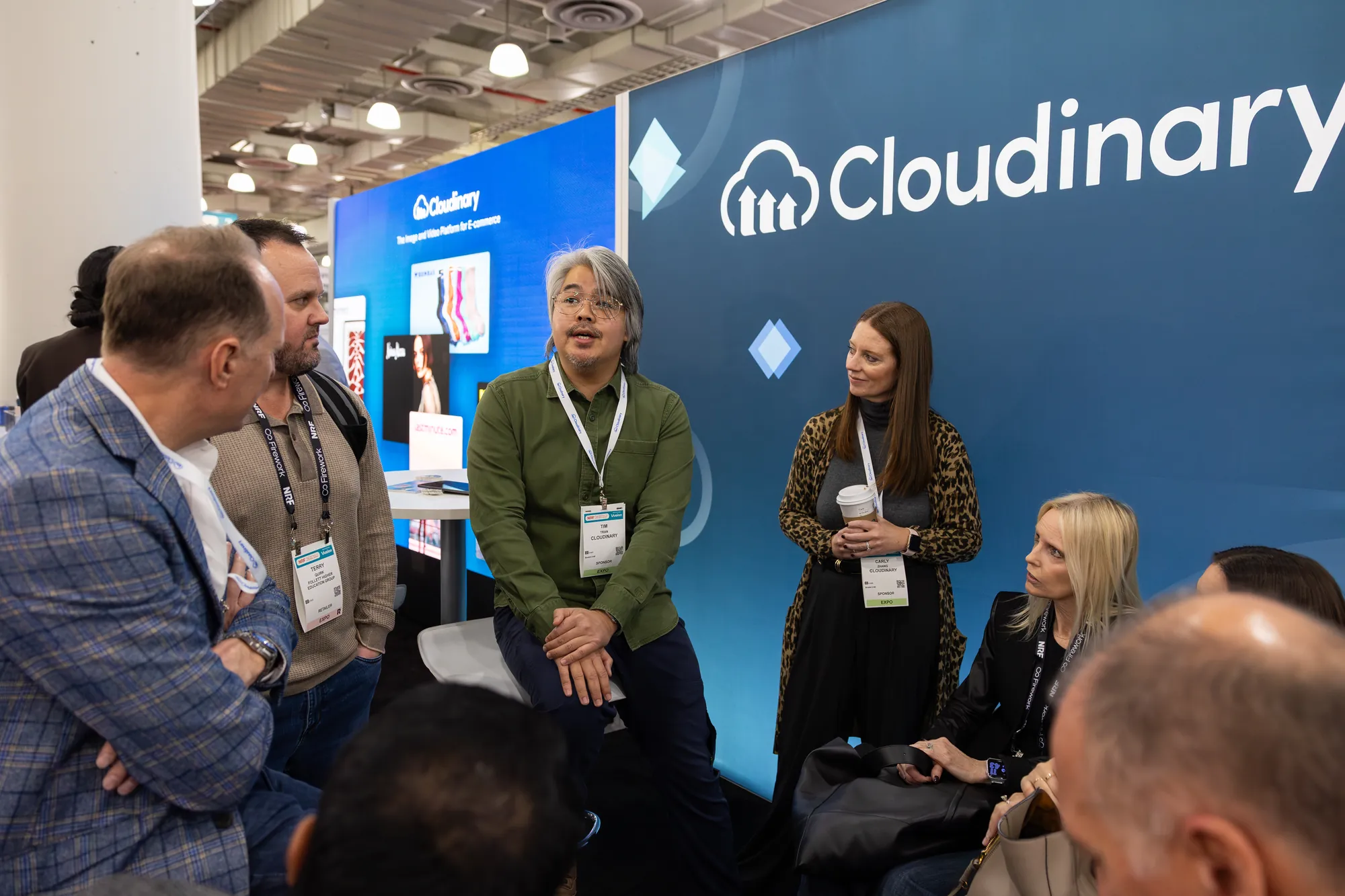 Visitors talking in the booth lounge in front of the Cloudinary LED wall