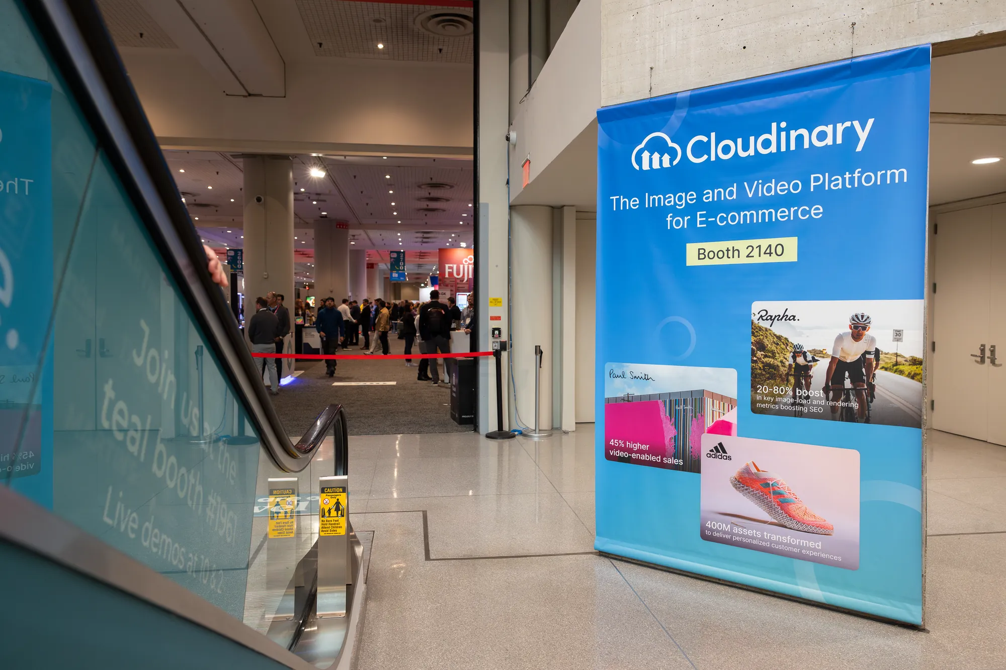 Cloudinary standee by the escalators pointing to Booth 2140