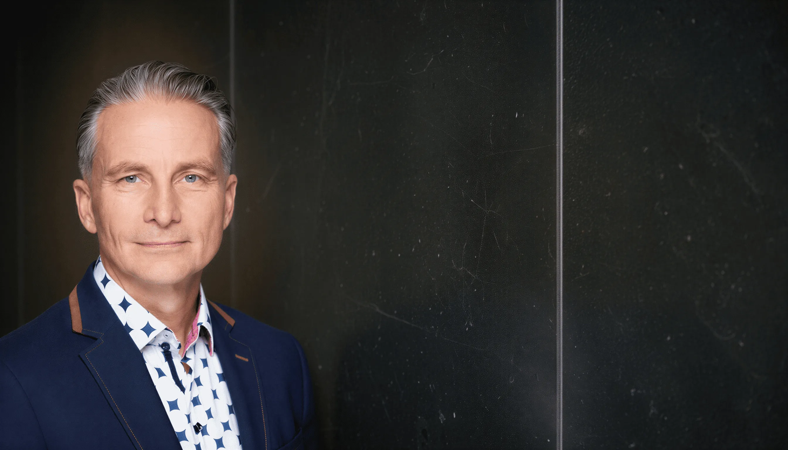 Julian Box, in front of a dark marble wall.
