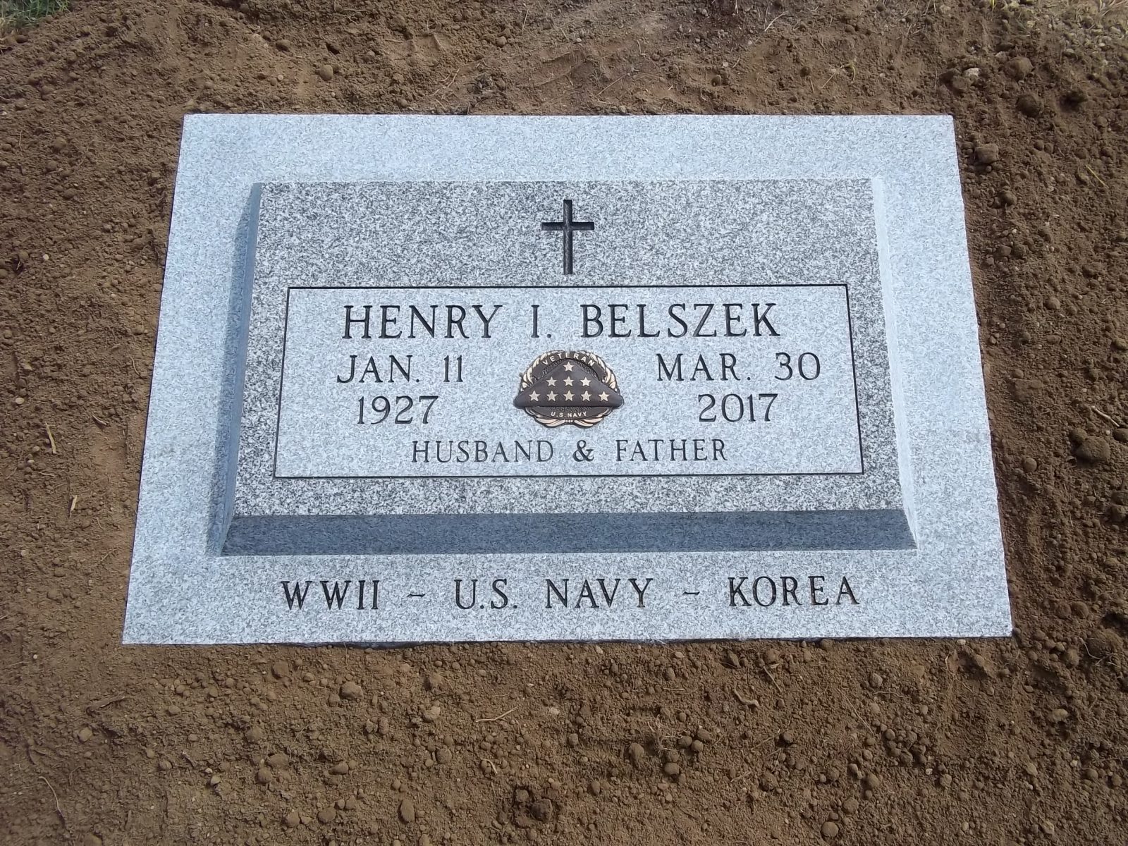 Grey granite flush marker with a carved emblem
