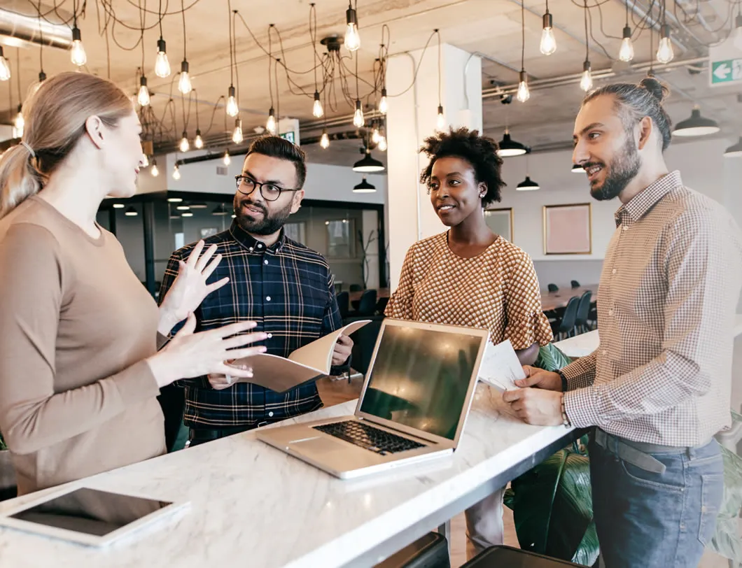 A small team talking around a laptop in an office