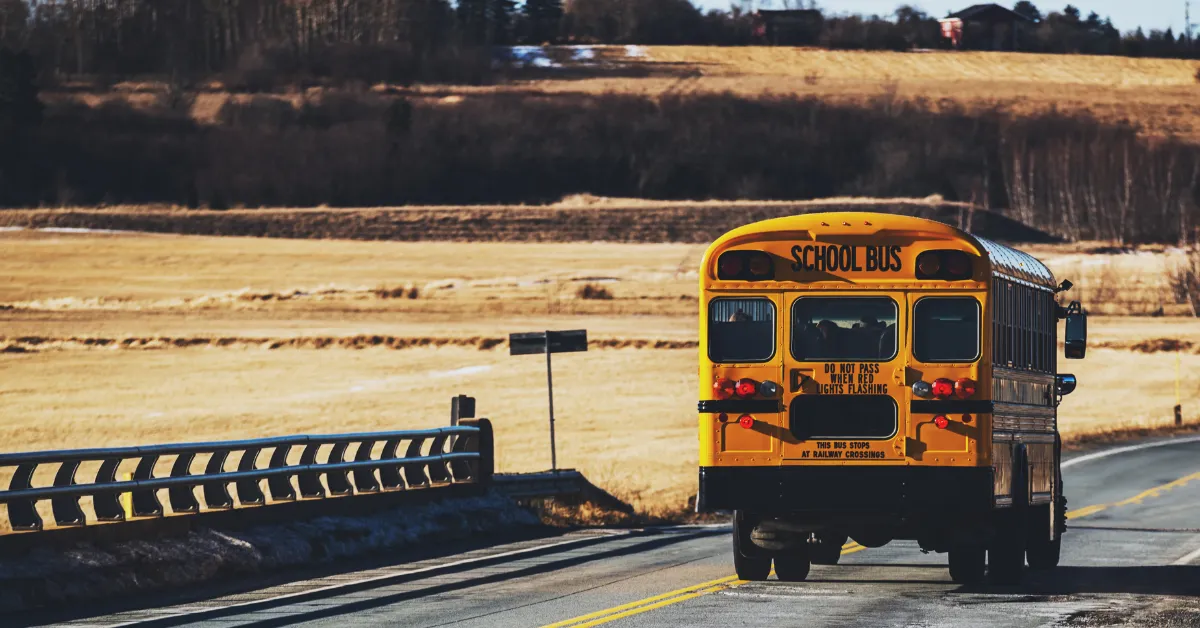 A yellow school bus on a rural road through open prairie