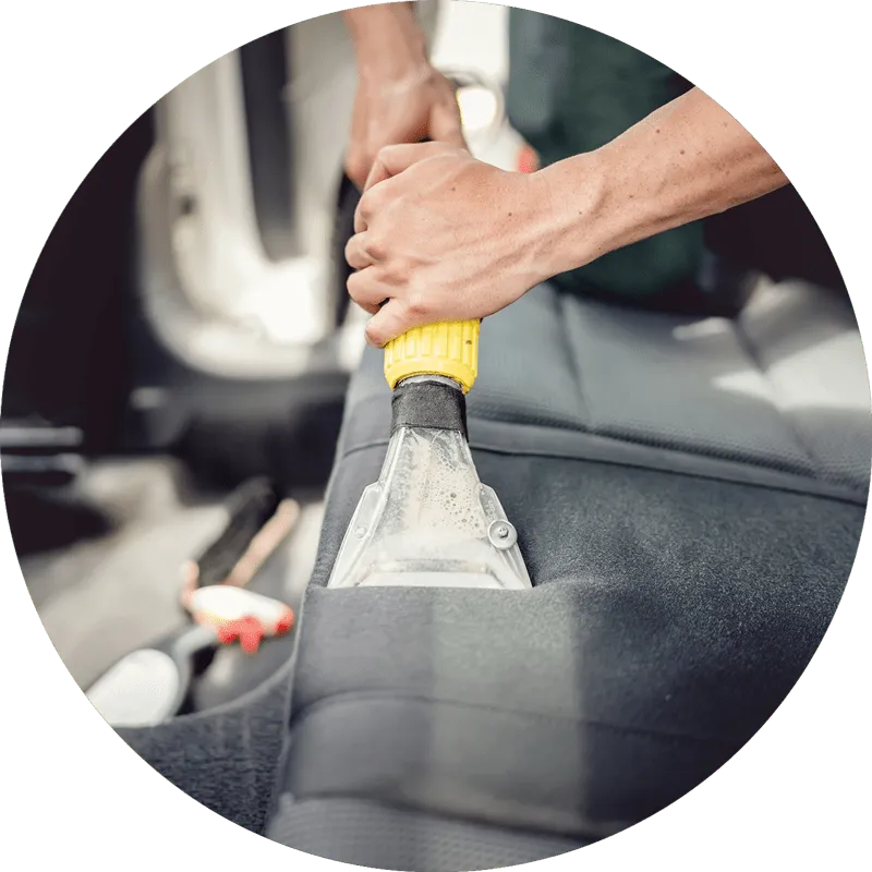 Carpet extractor cleaning a car seat during an interior detail