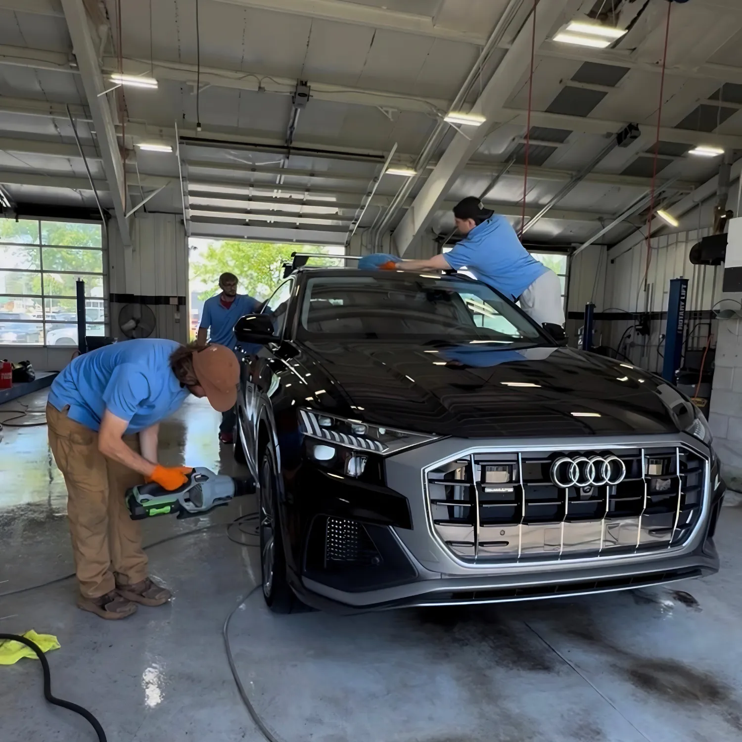 Three KBC Auto detailers working on a black Audi SUV inside our detailing shop in state college PA for ceramic coatings and tint and auto detailing
