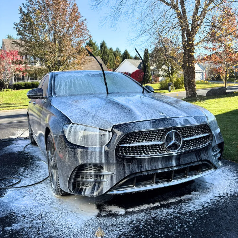 Mercedes-Benz sedan covered in foam during an exterior hand wash in a driveway mobile detail appointment