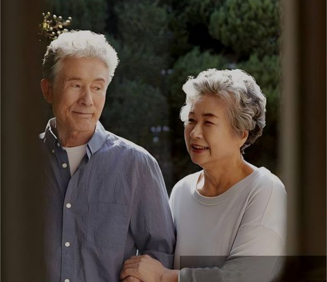 An older couple walking arm in arm outdoors, smiling