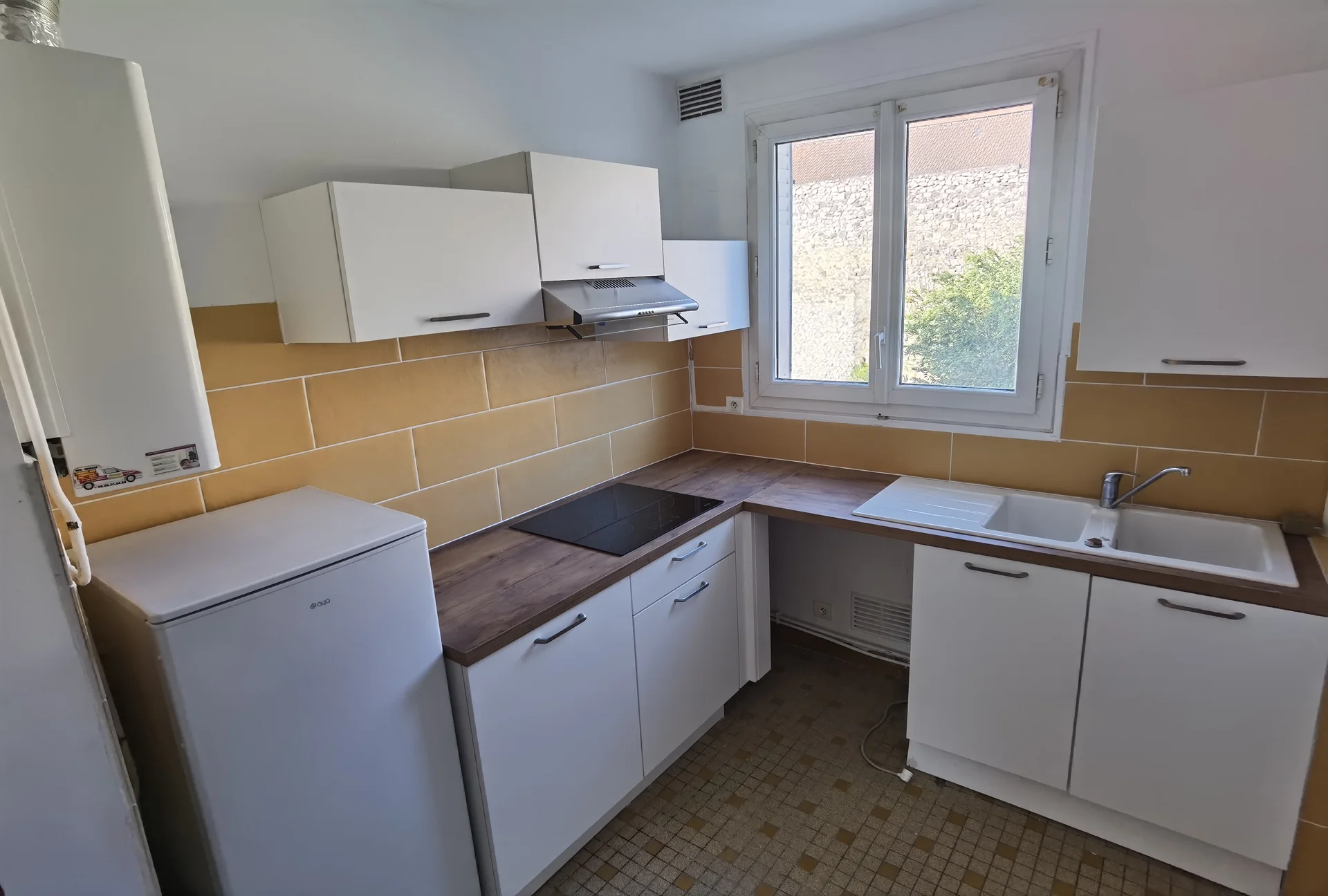 Cuisine en L avec meubles blancs, plan de travail bois et évier