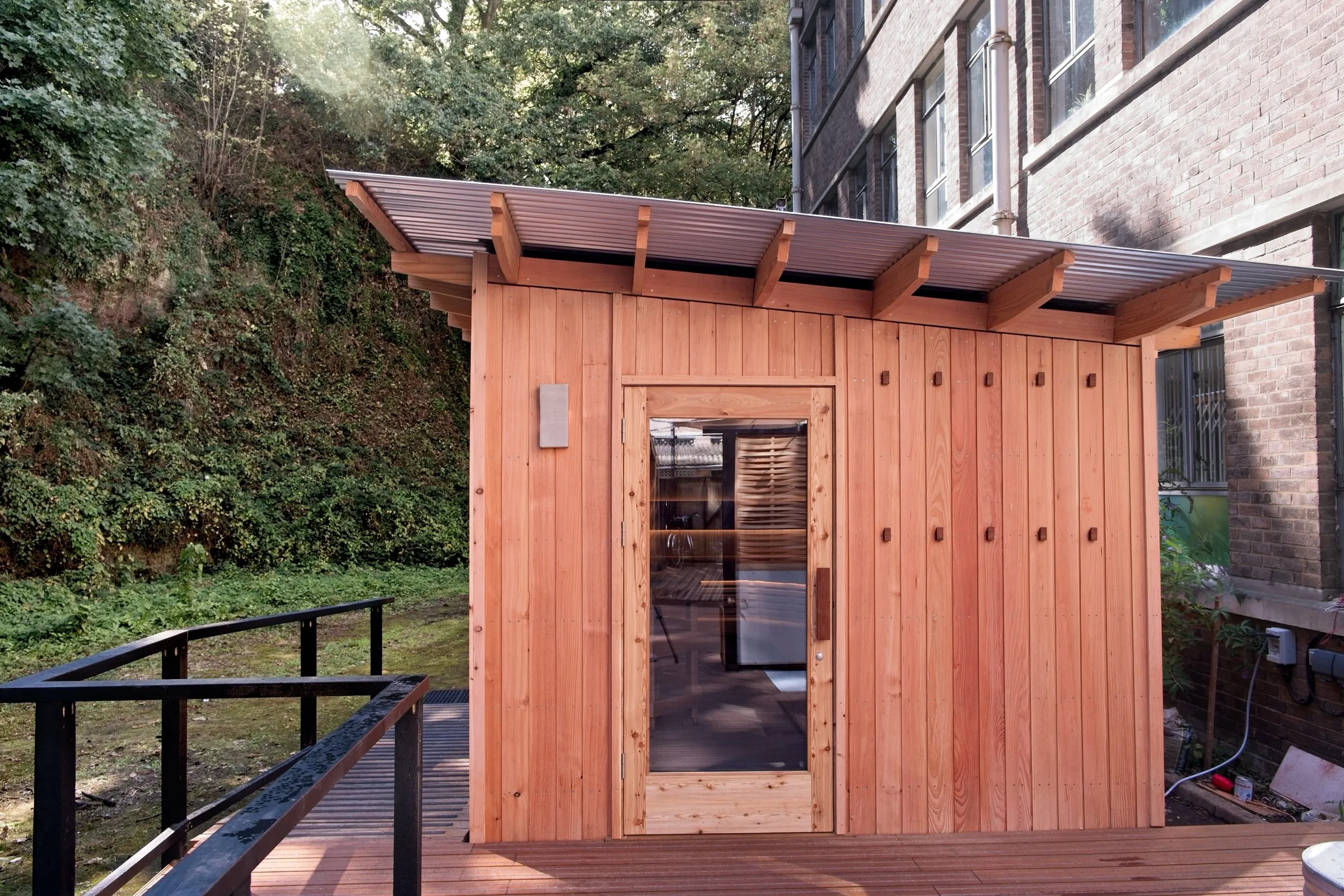 Front of the St Anne's timber sauna with glazed door, deep roof overhang and deck