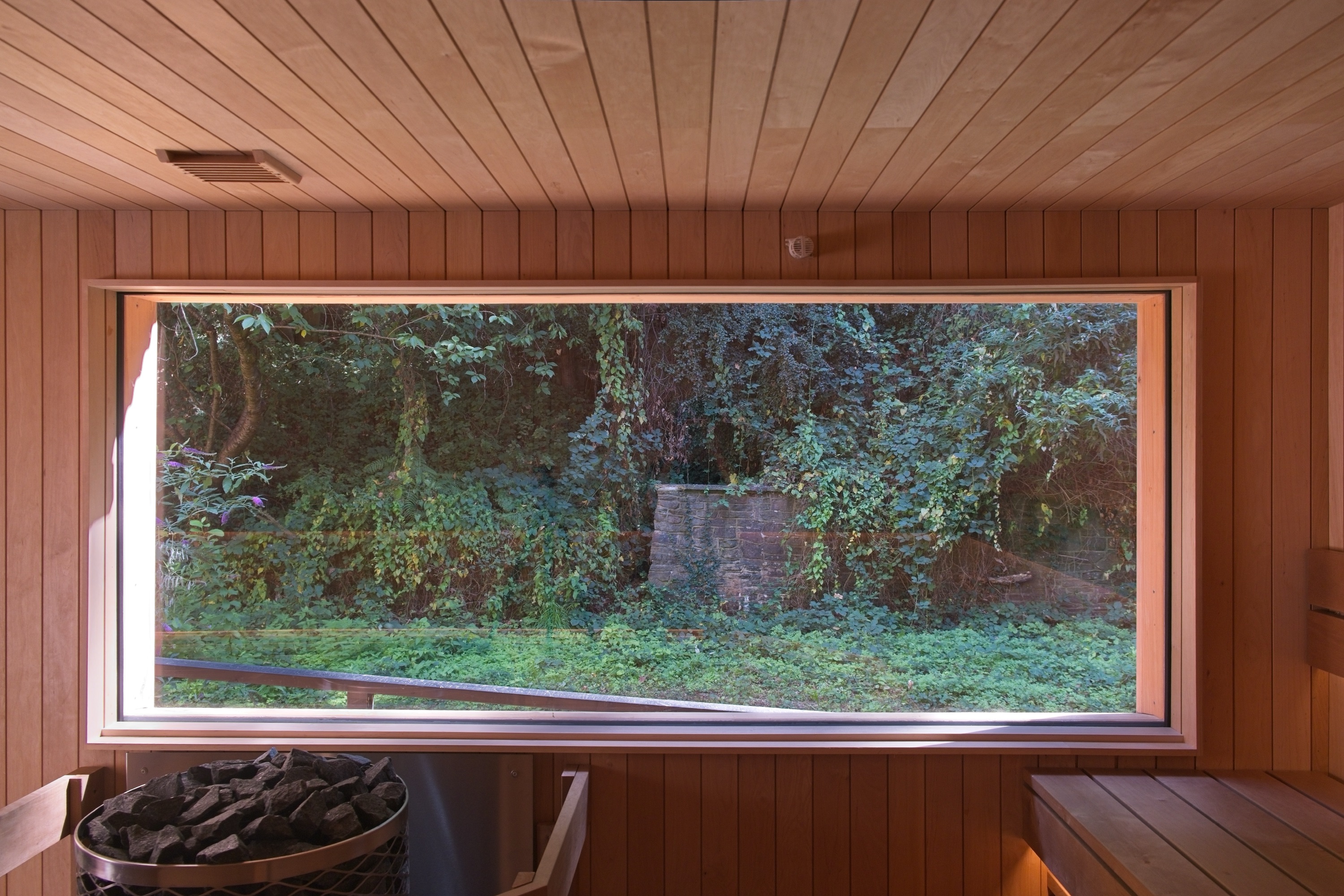 Large frameless sauna window looking out to the garden
