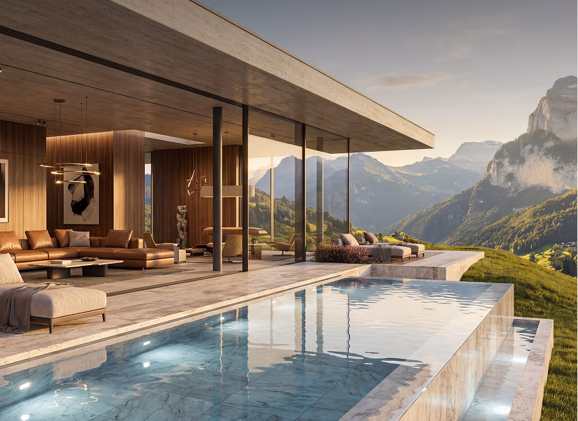 Modern house with large glass windows and a wooden ceiling, an outdoor infinity pool with underwater lights, beige poolside lounge chairs, and mountains in the background during sunset.