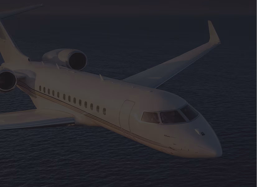 White private jet flying over a body of water at dusk or dawn.