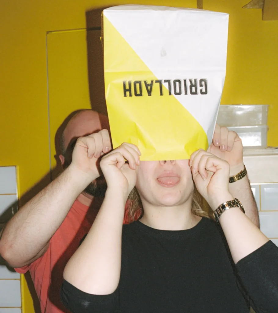 Griolladh employee wearing a paper bag on her head with her tongue out
