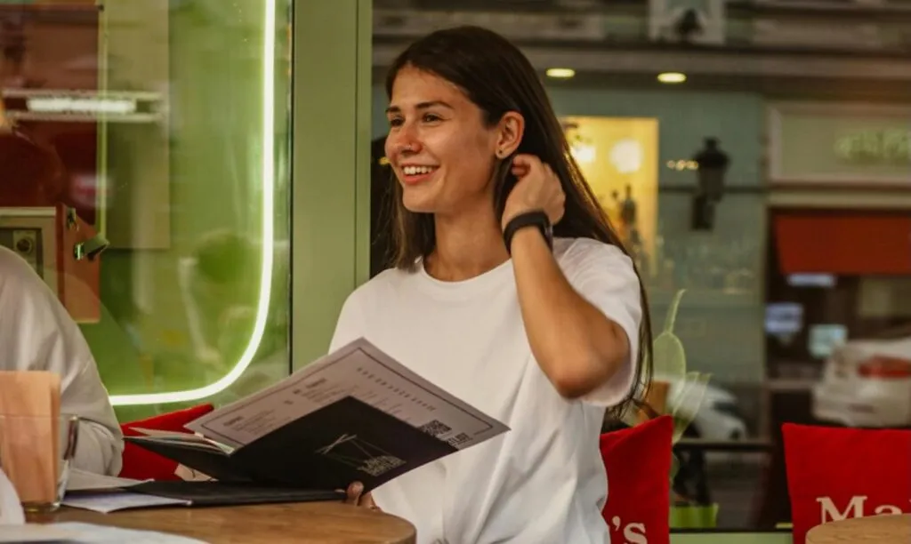 A woman sat at a restaurant holding a menu