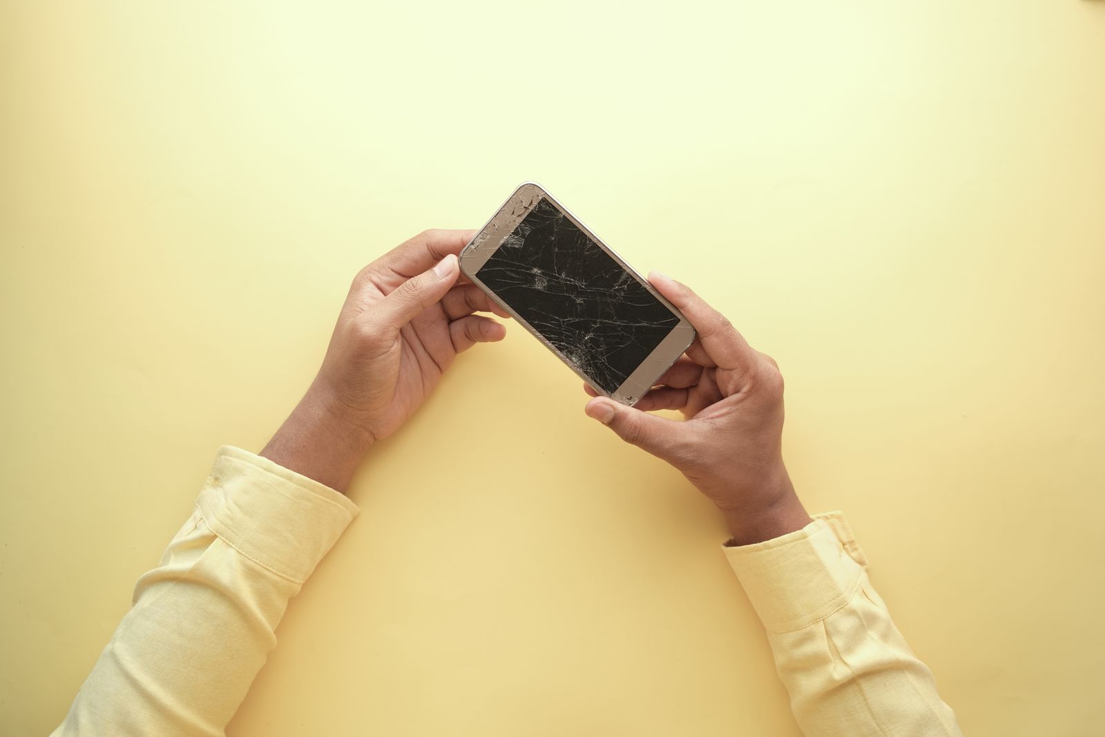 Hand die een smartphone met een gebarsten scherm vasthoudt