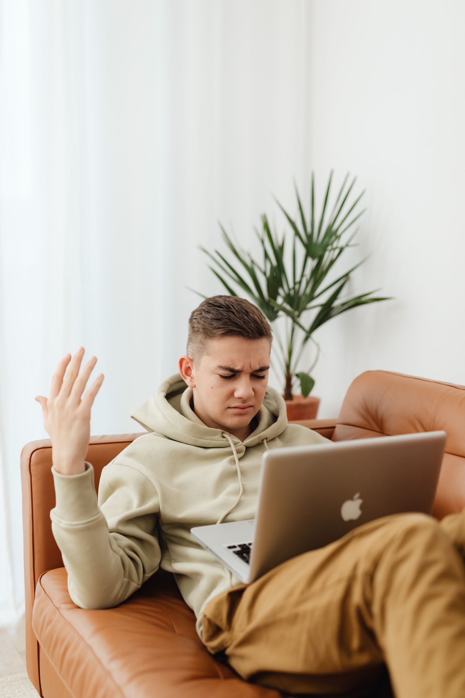Geïrriteerde man op de bank kijkt naar zijn trage laptop
