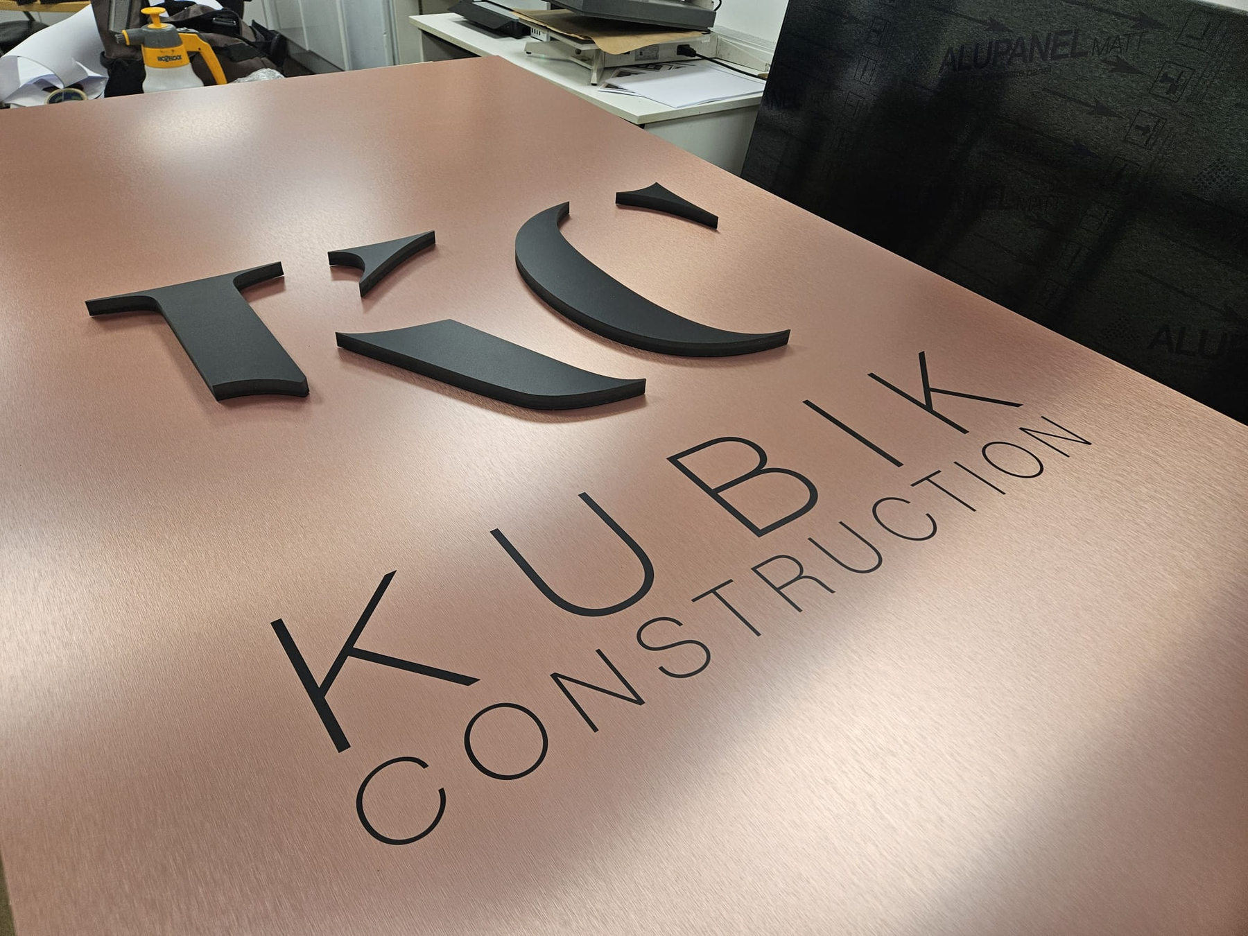 Close-up of fabricated raised black lettering on bronze ACM in workshop