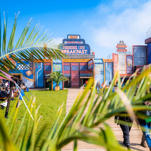 Palmbladeren voor de gekleurde gevels van Paradise City Breakfast en de Foodmarket op een zonnige dag