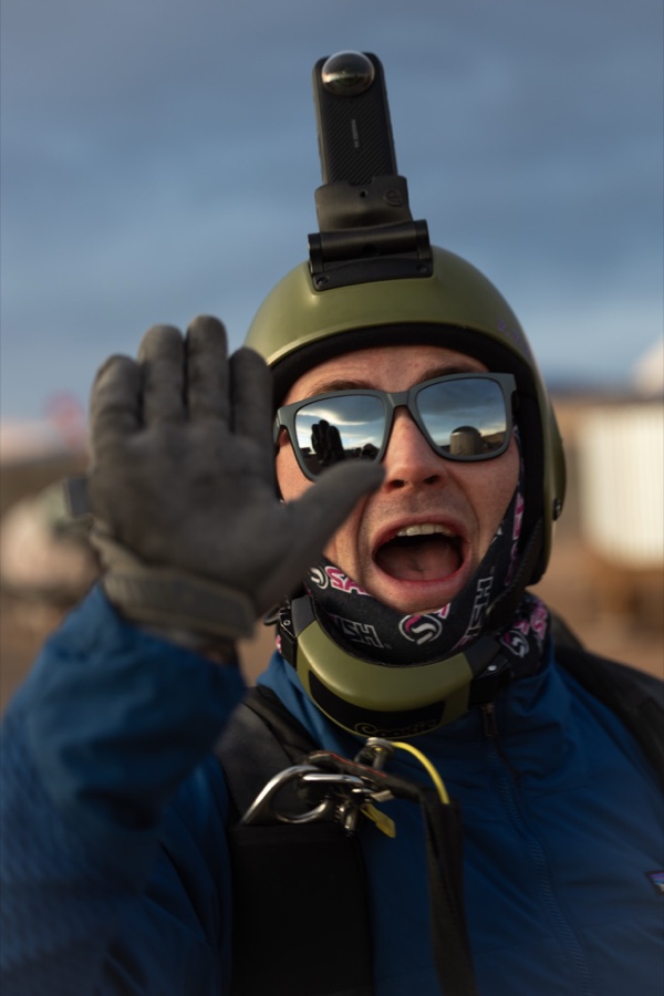 A jumper in helmet and shades shouting toward the camera before a load