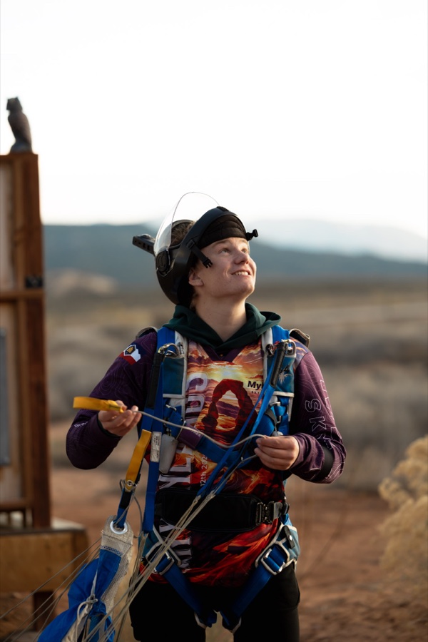 A jumper geared up and looking at the sky, red rock country behind