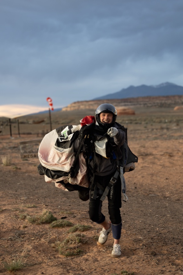 A jumper carrying a bundled canopy back across the desert after landing