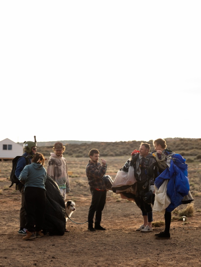Jumpers gathered around a canopy, packing at dusk