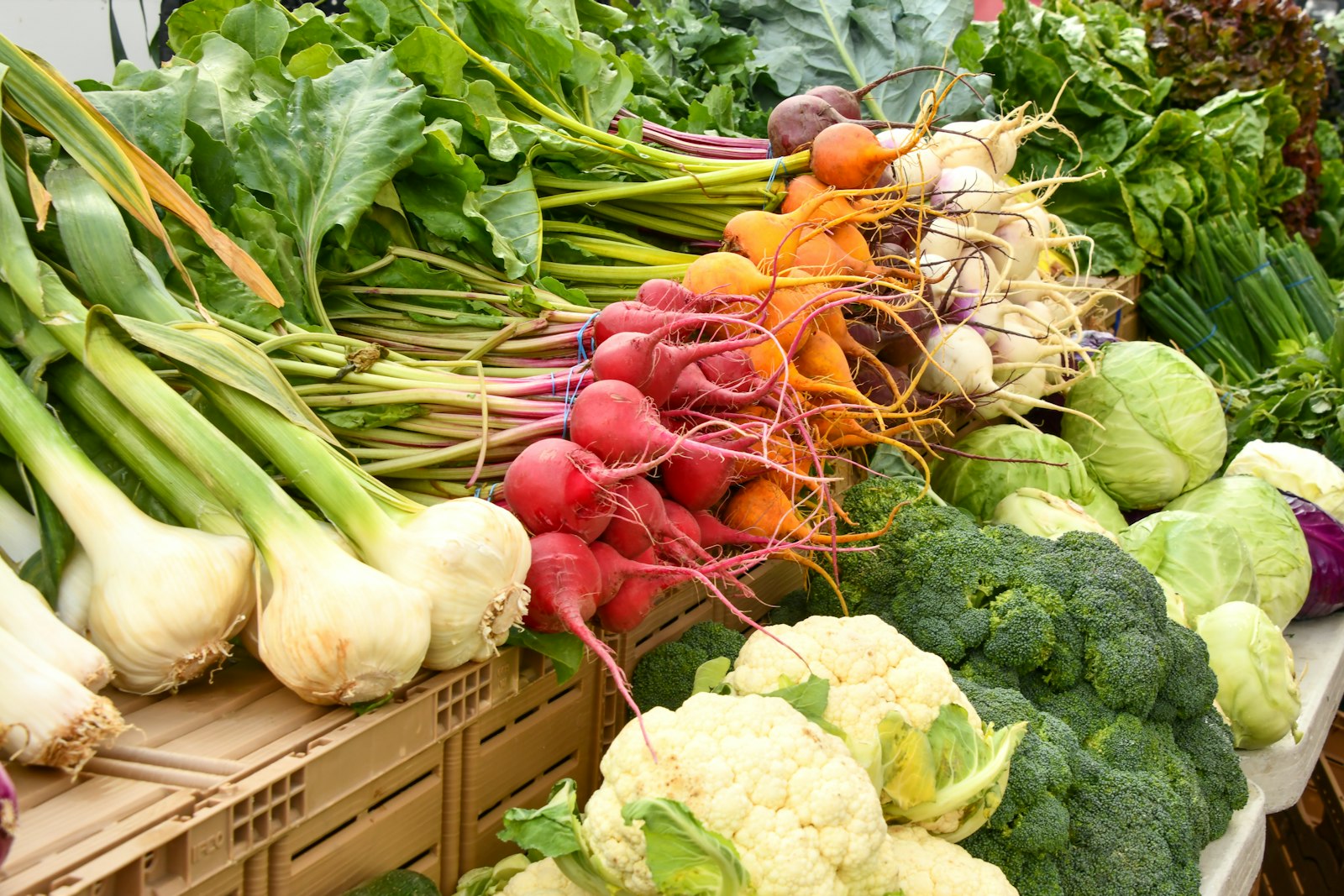 Market table of cauliflower, broccoli, radishes and onions