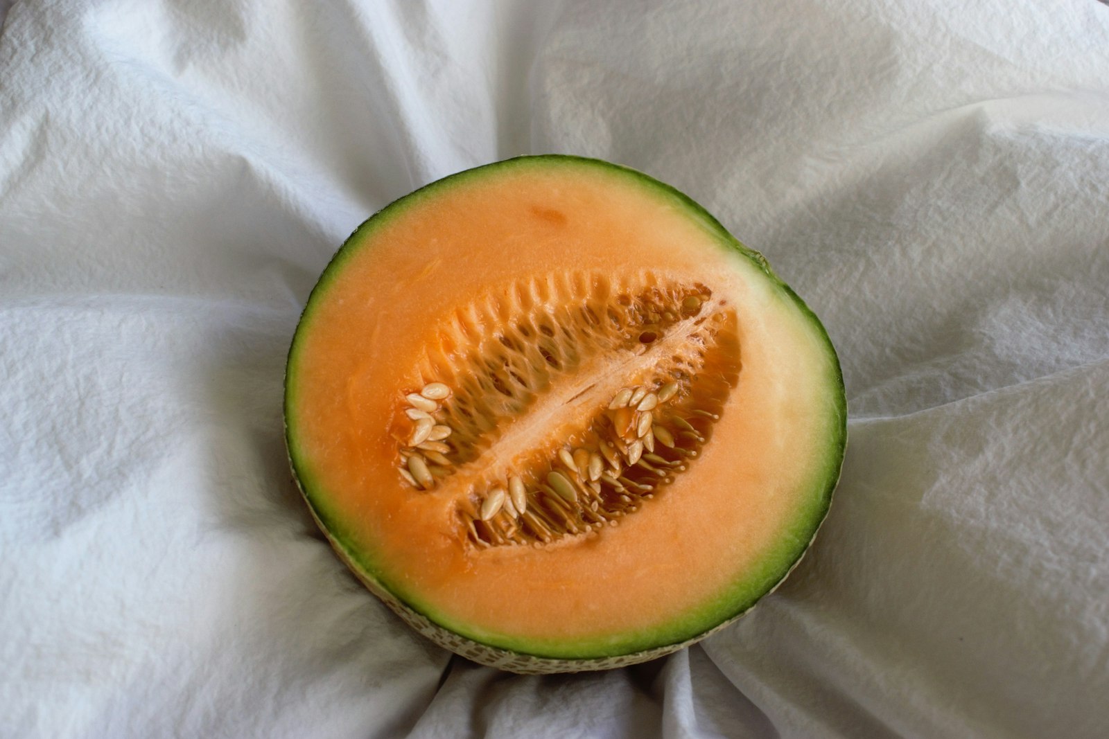 Halved cantaloupe on a white cloth