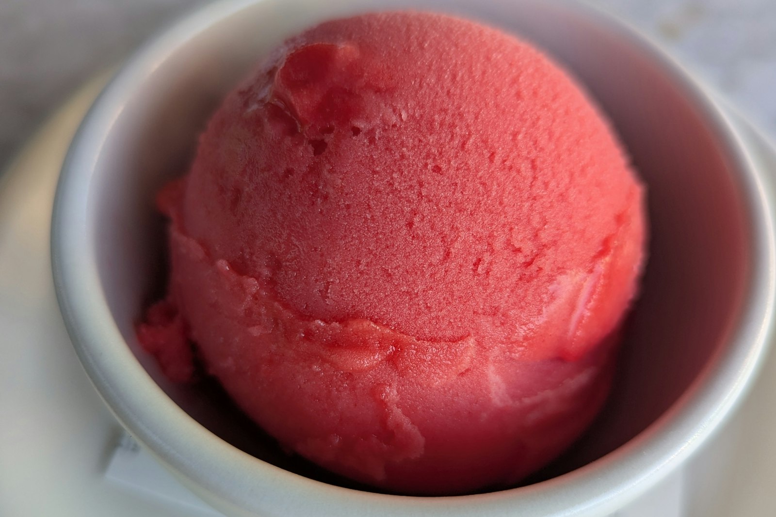 Scoop of pink sorbet in a white bowl