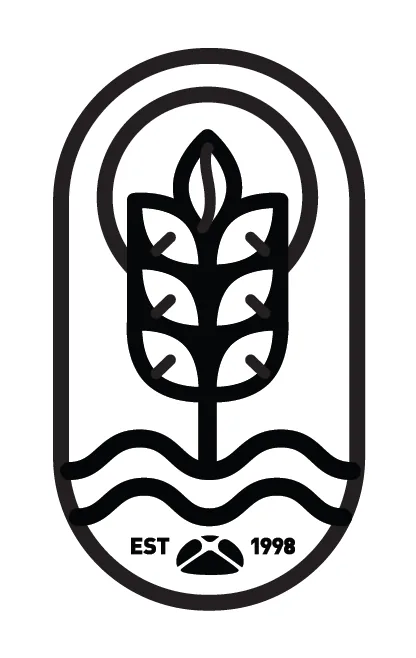 Palm Beach Bakery & Cafe icon: a black line-art wheat stalk rising from waves inside an arched frame marked "EST 1998"