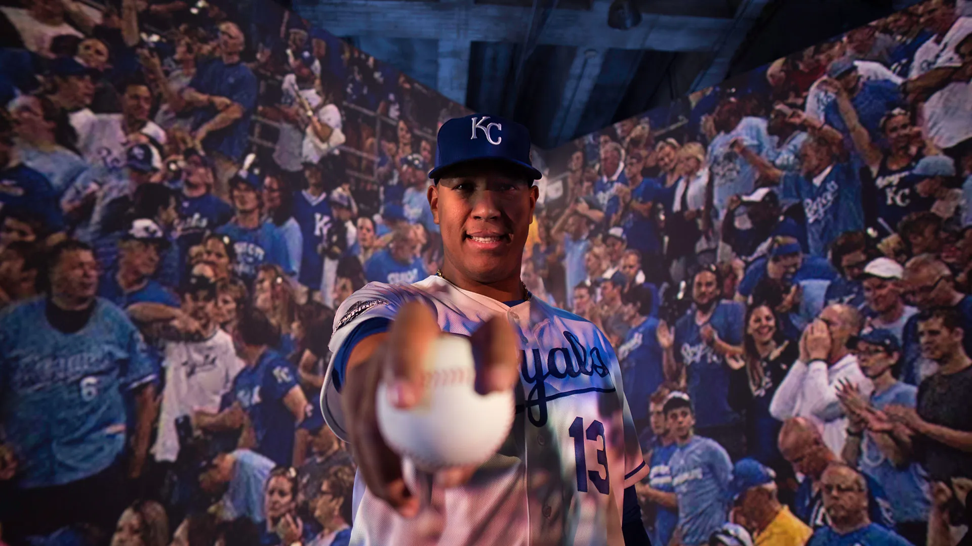 Salvador Perez holding out a baseball in front of a wall of Royals fans
