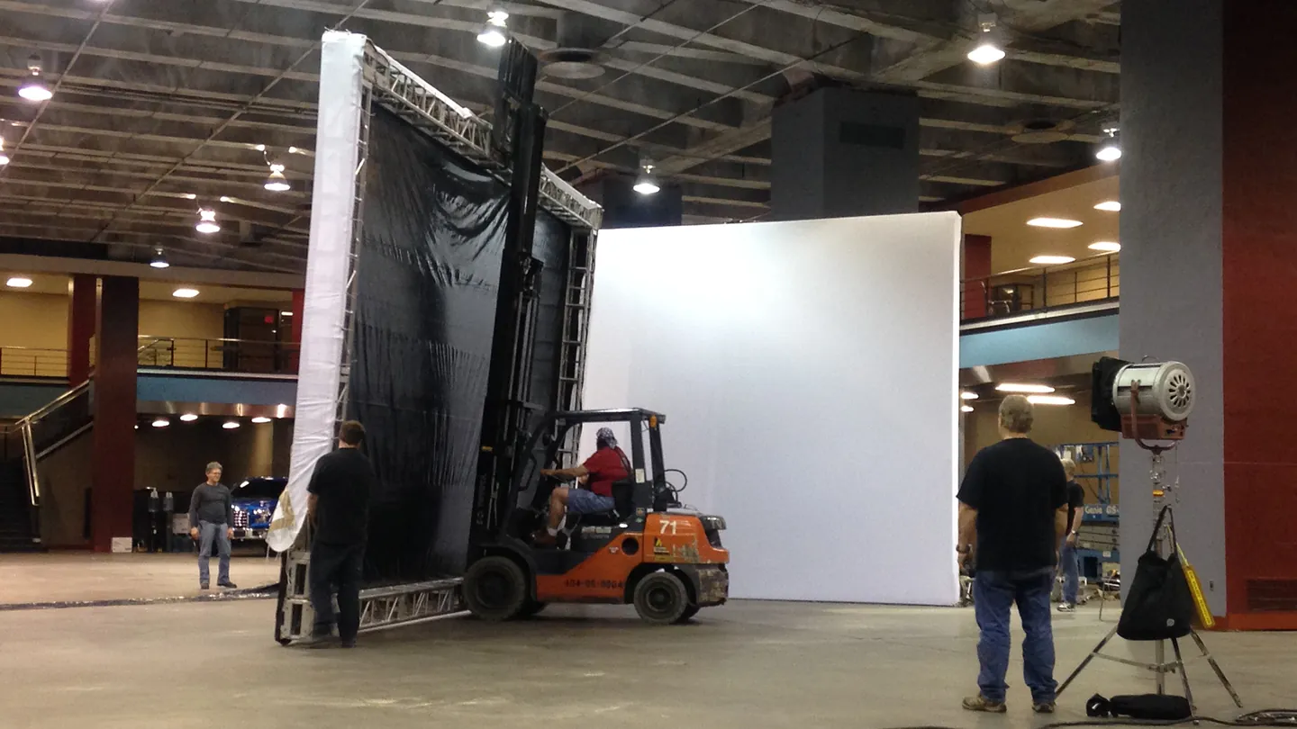 Crew moving a projection screen into place with a forklift during set build