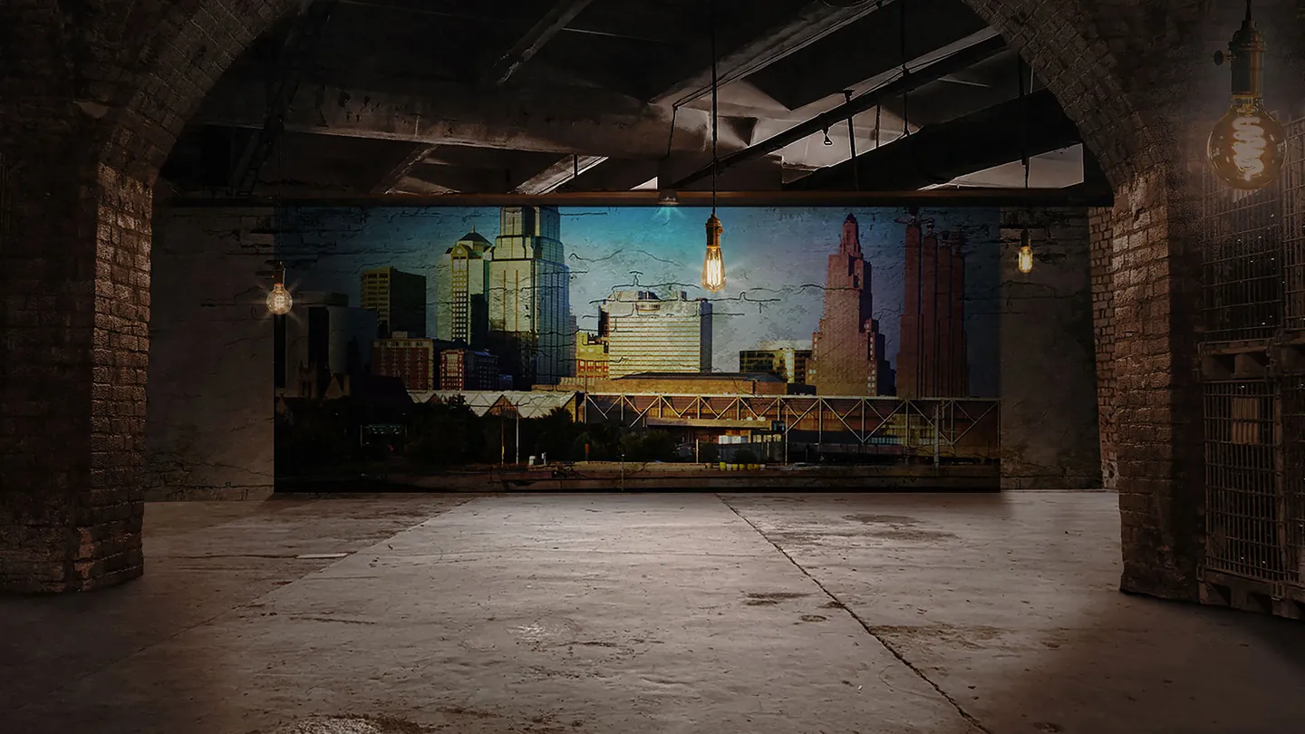 Storyboard frame: Kansas City skyline projected on a wall inside a brick warehouse