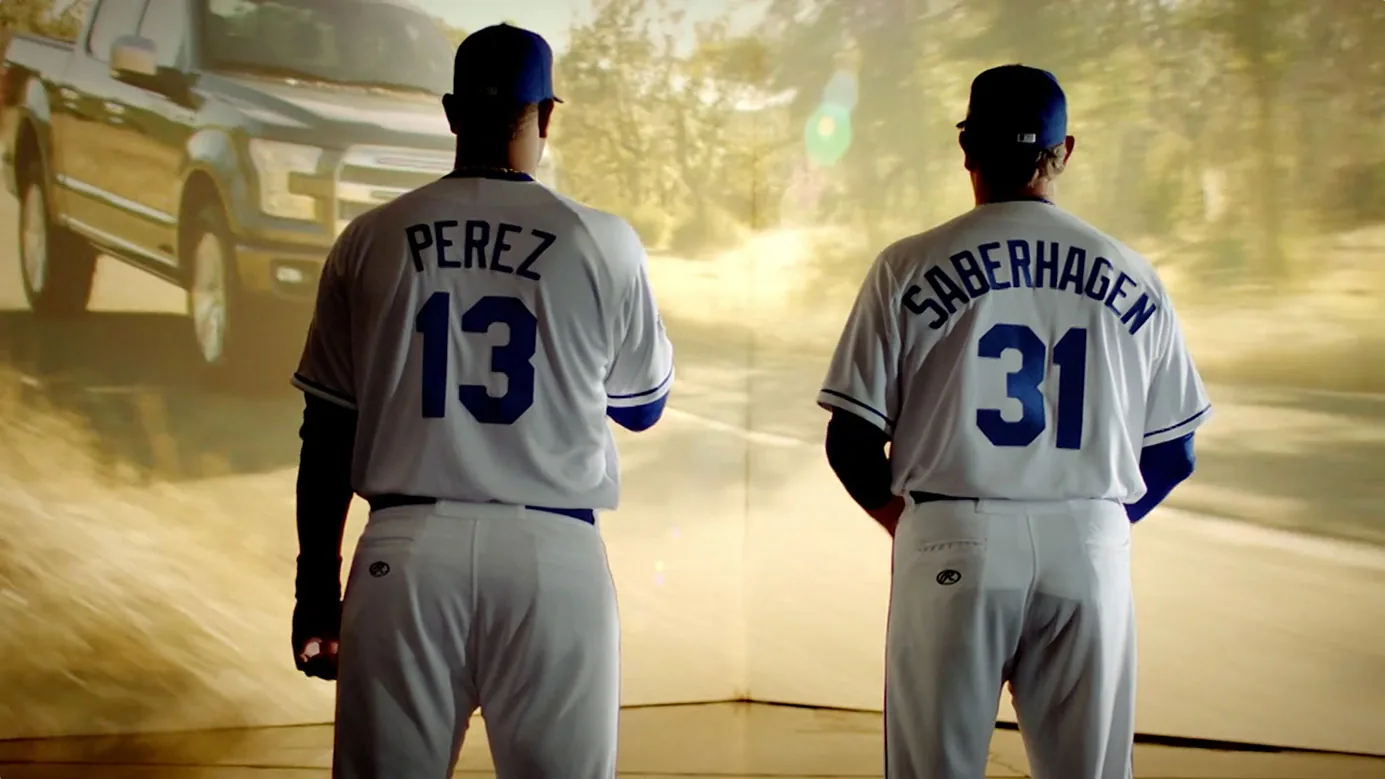 Salvador Perez and Bret Saberhagen in Royals jerseys watching a Ford F-150 on a projection wall