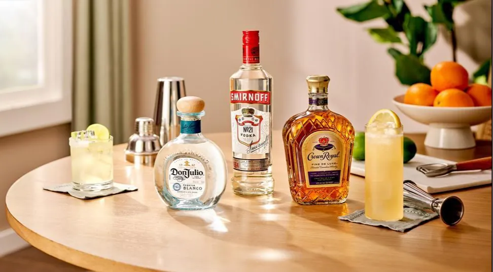 Don Julio, Smirnoff and Crown Royal bottles with cocktails on a table